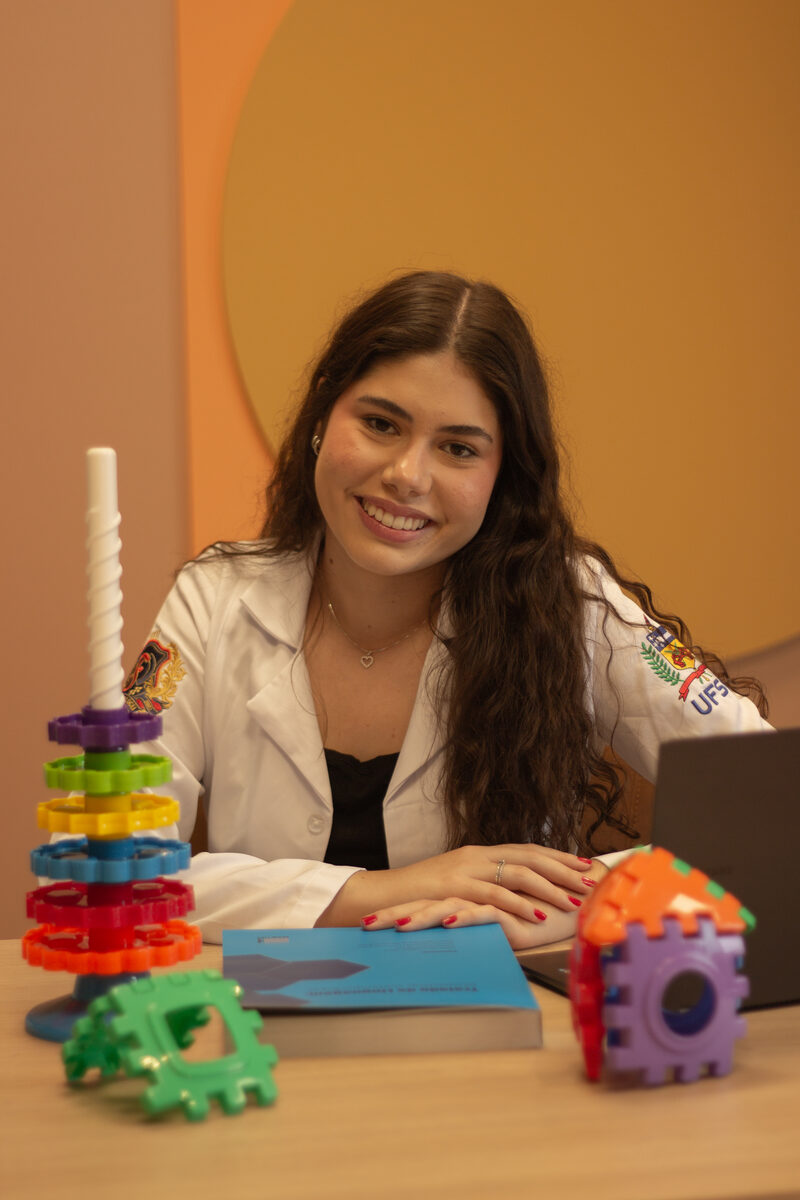 Luísa Dorigon, fonoaudióloga, sorrindo em seu consultório